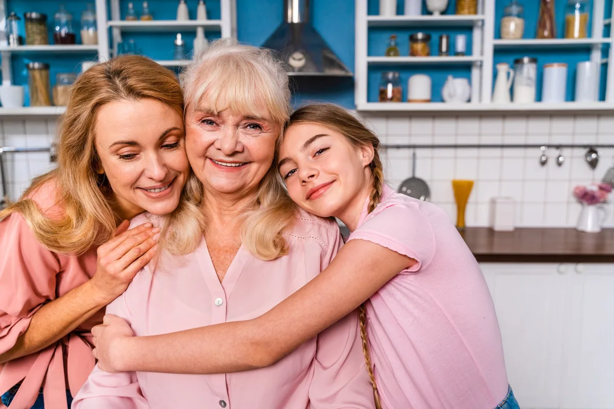 Drei Generationen einer Familie umarmen sich in der Küche