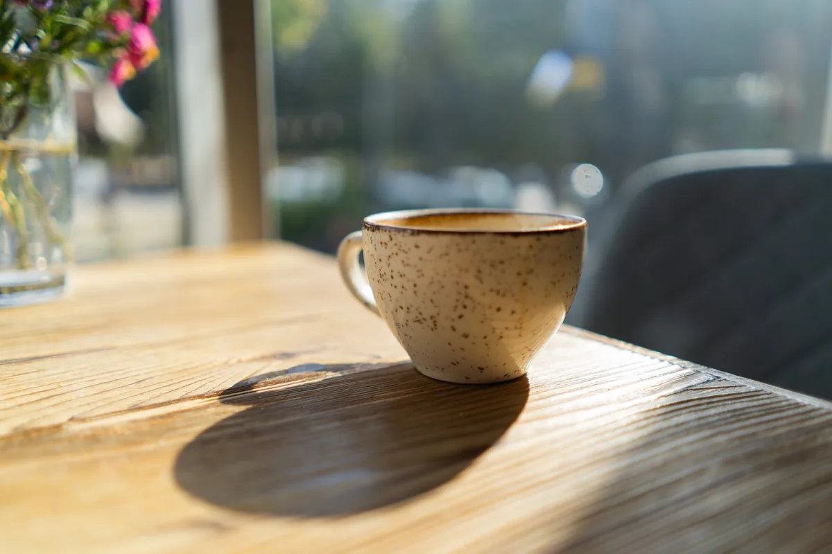 Kaffeetasse im Morgenlicht auf einem Holztisch
